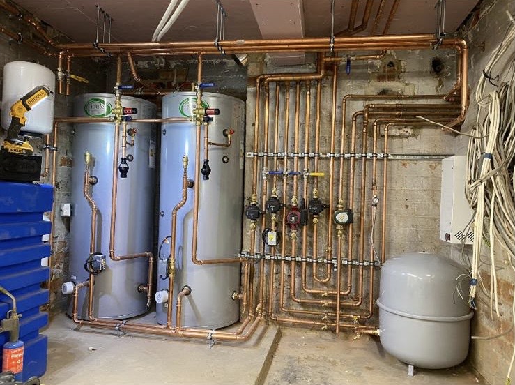 A tidy commercial plant room installation with twin hot water cylinders and precise copper pipework by PLA Plumbing & Heating
